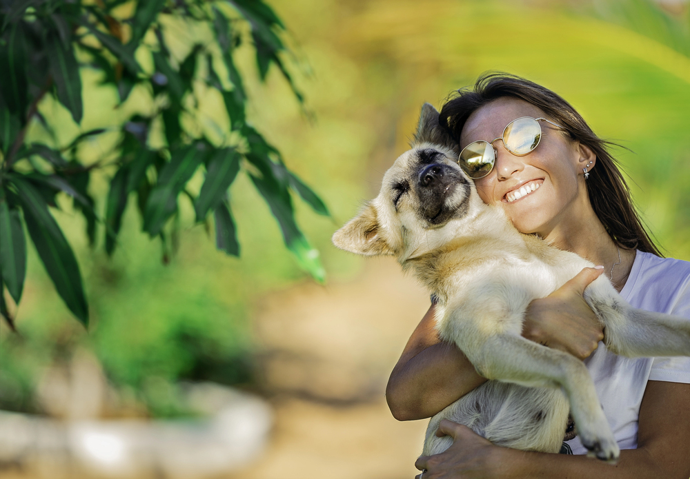 Woman happily hugging her dog outdoors